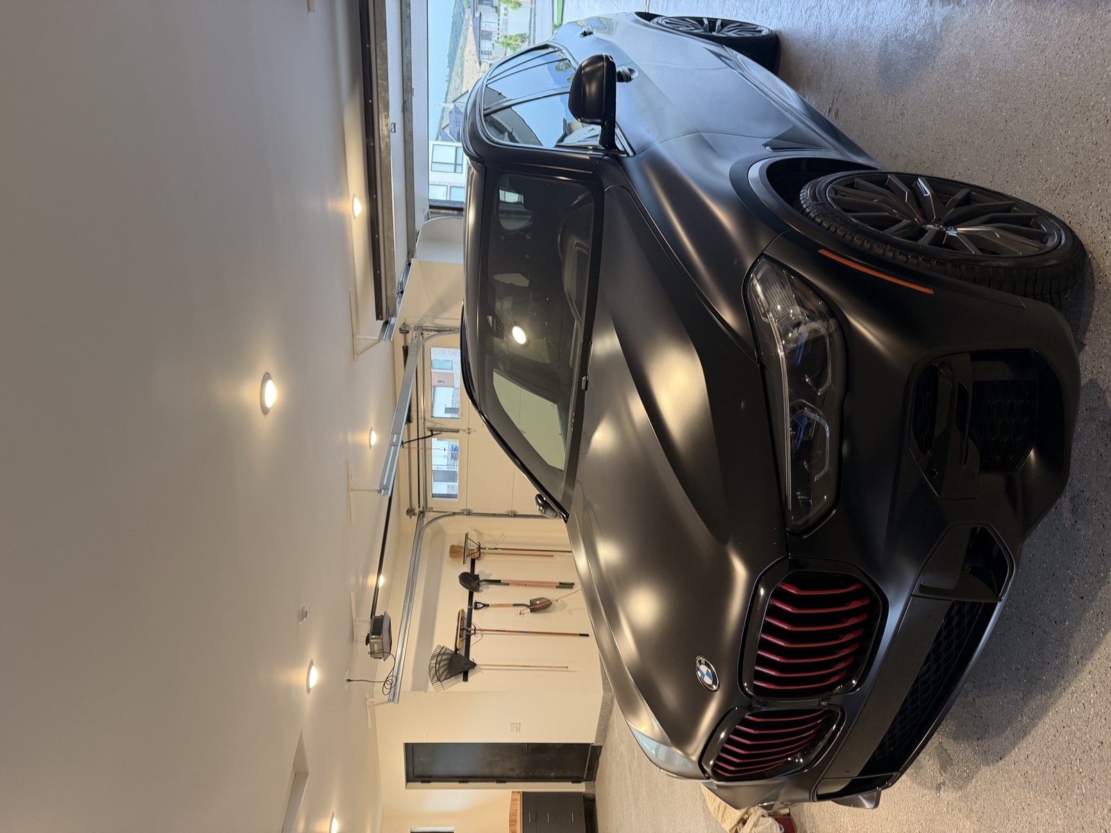 Matte black BMW SUV inside a bright, clean garage